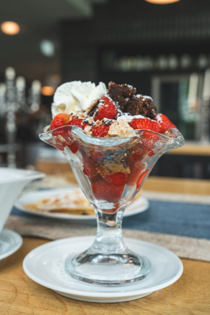 Strawberry dessert cup with brownie pieces, whipped cream, and chocolate shavings.