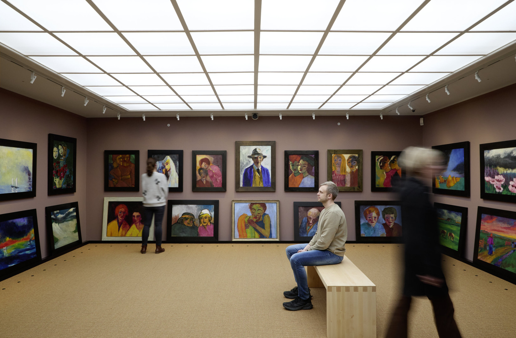 Three visitors view paintings by Emil Nolde in the Picture Gallery of the Nolde House.