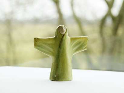 Ceramic figure of an angel with yellow and green glaze and dark accents.