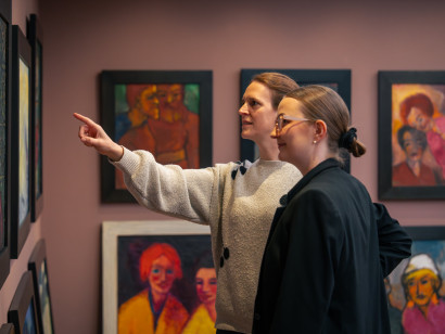 Two female visitors are looking at a painting by Emil Nolde in the gallery; one of them points towards the artwork with an outstretched hand.